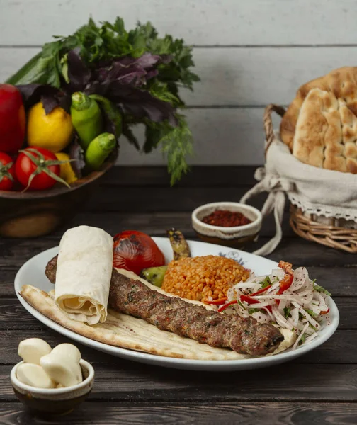 Adana kebab pitakenyéren, bulgárral és hagymakarikával tálalva. — Stock Fotó