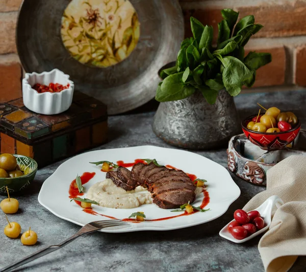 Irisan steak daging sapi disajikan dengan kentang tumbuk di piring yang dihias dengan saus merah — Stok Foto