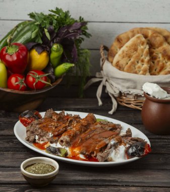 İskender kebabı domates sosu ve yoğurt ile süslenmiş, ızgara sebzelerle servis ediliyor.