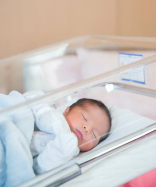 Yeni doğan bebek hastane beşiğinde yeni doğan kıyafetleriyle uyur.