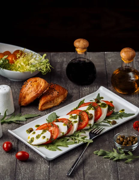 Platte mit Carpese-Salat garniert mit Basilikumblättern und Oliven — Stockfoto