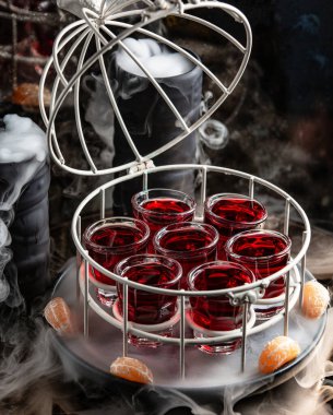 Kafeste servis edilen kırmızı kadehle tütsülenmiş tencerenin üstü açık.