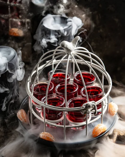 Copo de shots com bebida vermelha servido em bolo na panela defumada — Fotografia de Stock