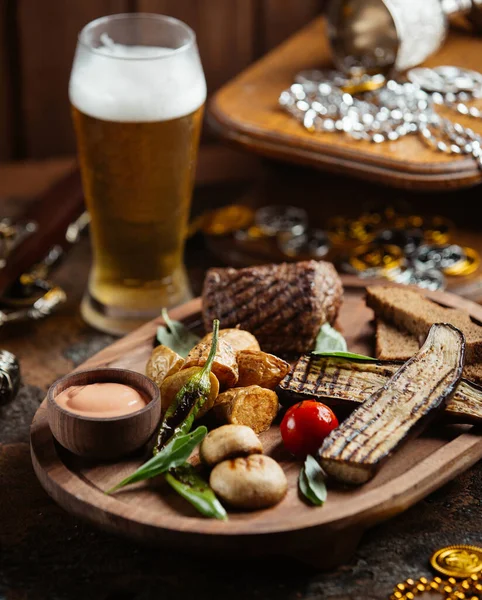 Holzplatte mit Rindersteak mit gegrillten Auberginen, Kartoffeln, Pilzen und Sauce — Stockfoto