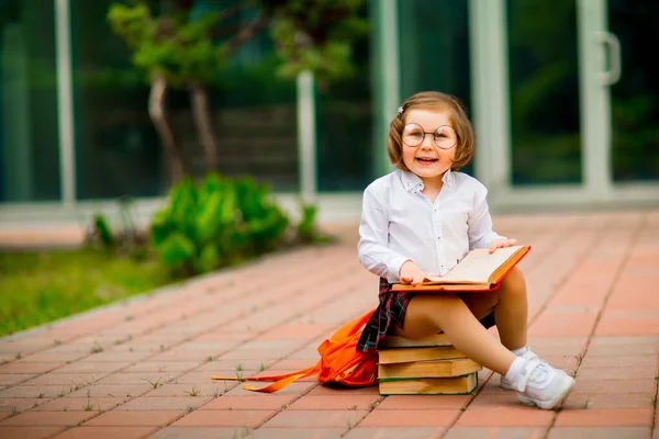 Liten Flicka Skoluniform Och Glasögon Sittandes Hög Med Böcker Nära — Stockfoto