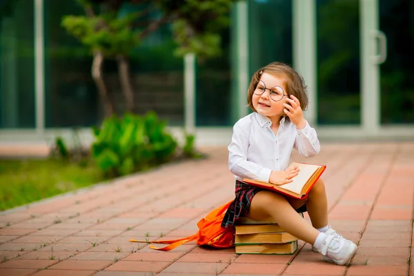 Ein Kleines Mädchen Schuluniform Und Brille Sitzt Auf Einem Stapel — Stockfoto