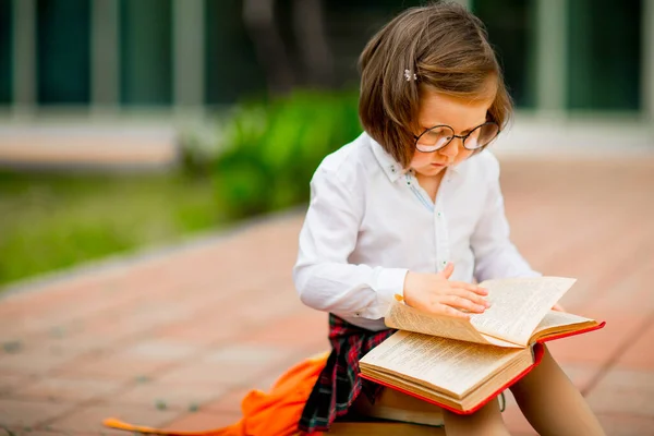 Ein Kleines Mädchen Schuluniform Und Brille Sitzt Auf Einem Stapel — Stockfoto