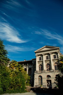 Güzel eski bina, mavi gökyüzü ve yeşil ağaçların arka planında