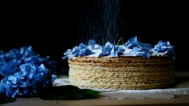 Beyaz pudra şekeri mavi çiçeklerle süslenmiş waffle kekinin üzerine serpilmiştir.