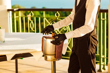 Bir kova soğuk şampanya, üniformalı bir garson ve siyah lateks eldivenler.