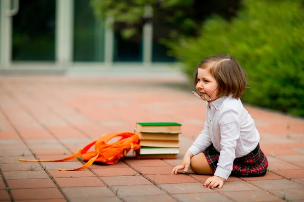 Menina em uniforme escolar e óculos, com livros didáticos — Fotografia de Stock