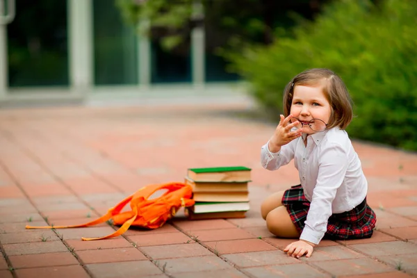 Kleines Mädchen in Schuluniform und Brille, mit Schulbüchern — Stockfoto