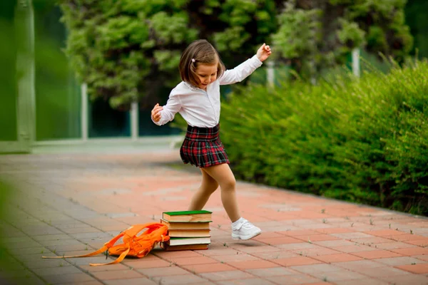 Mała dziewczynka w szkolnym mundurku i okularach, z podręcznikami — Zdjęcie stockowe