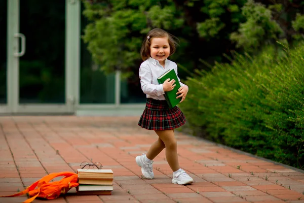 Mała dziewczynka w szkolnym mundurku i okularach, z podręcznikami — Zdjęcie stockowe