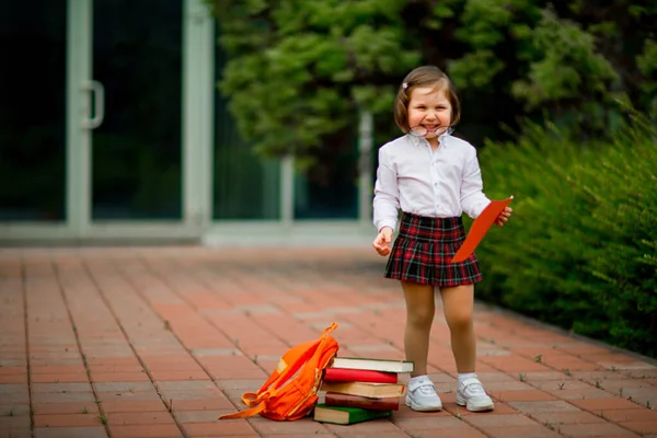 学校の制服を着た少女が学校の近くに立ち紙やテキストとコピーのためのスペースのあるレイアウトで — ストック写真