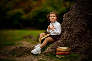 Okul üniformalı bir kız, 1 Eylül 'de okul arasında büyük bir ağacın yanında sandviç yiyor.