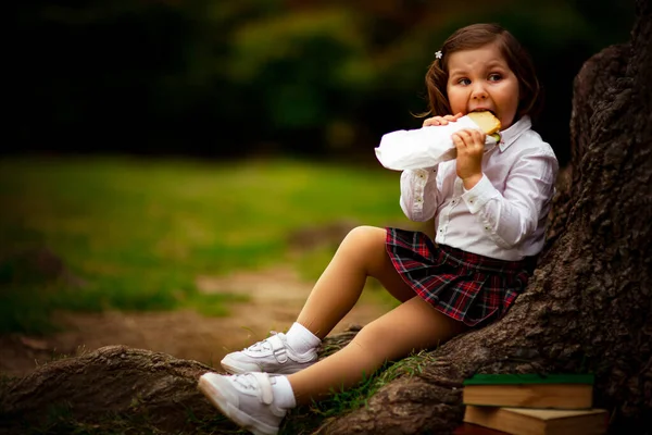 Uma Menina Uniforme Escolar Comendo Sanduíche Perto Uma Árvore Grande — Fotografia de Stock