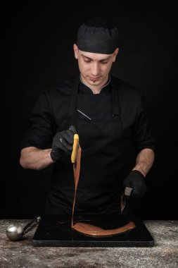 Chocolatier siyah çikolata yapma sürecinde üniforma. Yapma tatlım. Fotoğraf Studio, siyah bir arka plan
