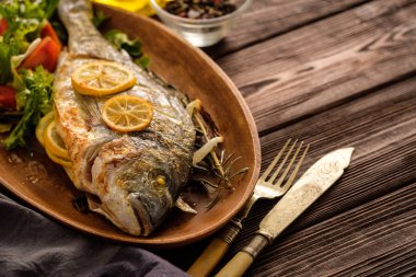 Limon, kekik, biberiye ve ahşap masa üzerinde taze salata Izgara Dorado