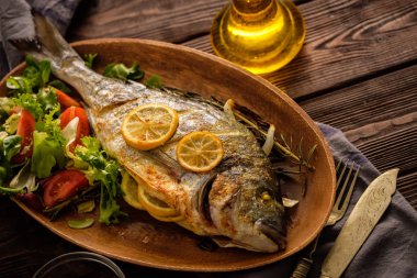 Limon, kekik, biberiye ve ahşap masa üzerinde taze salata Izgara Dorado