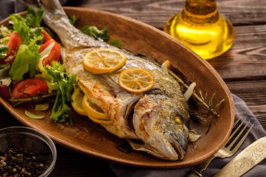 Limon, kekik, biberiye ve ahşap masa üzerinde taze salata Izgara Dorado