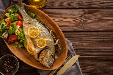 Limon, kekik, biberiye ve ahşap masa üzerinde taze salata Izgara Dorado