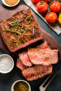 Üzerinde kesme tahtası ızgara sebzeli biftek dilimlenmiş. Üstten görünüm.