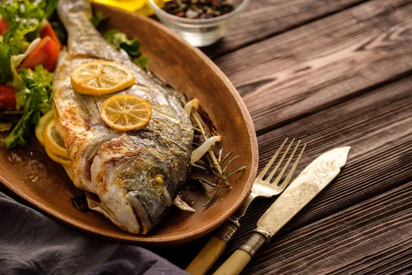 Limon, kekik, biberiye ve ahşap masa üzerinde taze salata Izgara Dorado