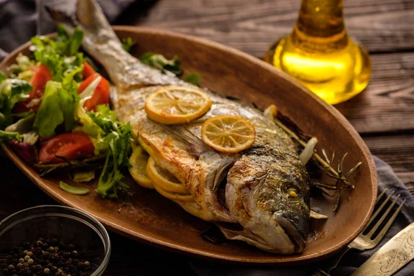 Limon, kekik, biberiye ve ahşap masa üzerinde taze salata Izgara Dorado