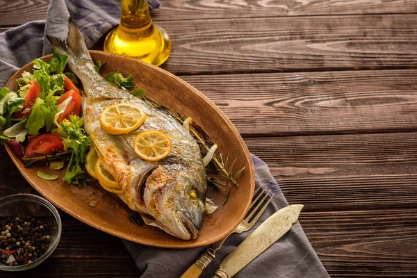 Limon, kekik, biberiye ve ahşap masa üzerinde taze salata Izgara Dorado