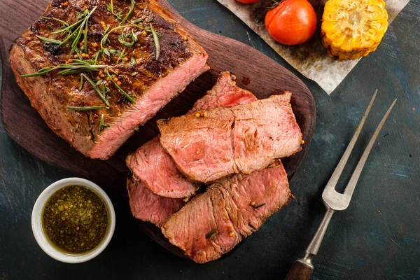 Üzerinde kesme tahtası ızgara sebzeli biftek dilimlenmiş. Üstten görünüm.