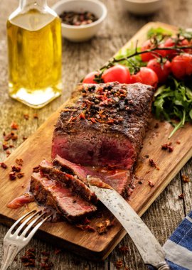 Üzerinde kesme tahtası ızgara sebzeli biftek dilimlenmiş 