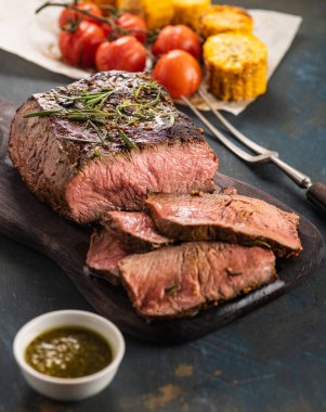 Üzerinde kesme tahtası ızgara sebzeli biftek dilimlenmiş 