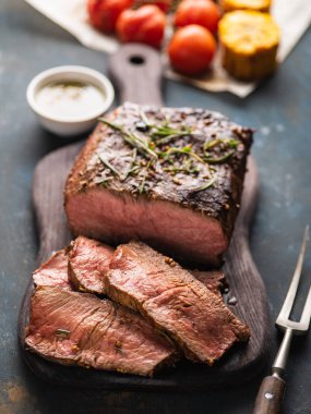 Üzerinde kesme tahtası ızgara sebzeli biftek dilimlenmiş 