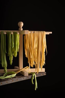Freshly prepared Tagliatelle paste is dried on a wooden drier. Traditional italian cuisine. clipart