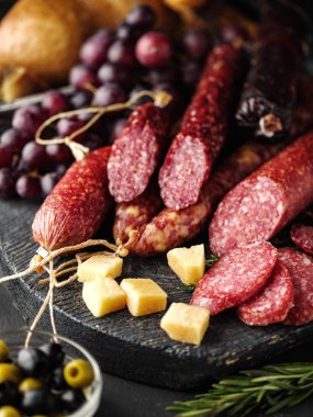 Salam rustik tarzda dilimlenmiş. Salam sosis. Peynir, üzüm ve zeytin ile farklı sosis.