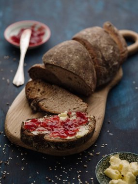 Ev yapımı ahşap bir masa ve bir sandviç tereyağı ve reçel ile çavdar ekmeği dilimlenmiş