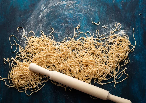卵麺を乾燥させます 青い木製の背景に生の新鮮なスパゲッティ トップ ビュー — ストック写真