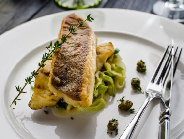 Beyaz tabak haşlanmış pırasa bir yastık üzerine pisi balığı fileto