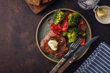 Sarımsak tereyağı ve sebze ızgara sığır eti biftek. Et ızgara dolmalık biber, brokoli ve soğan. Üstten görünüm. boşaltmak.