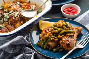 Bezelye, fasulye ve taze otlar ile pişmiş tavuk budu. Tavuk drumsticks lezzetli sause ve yeşillik ile