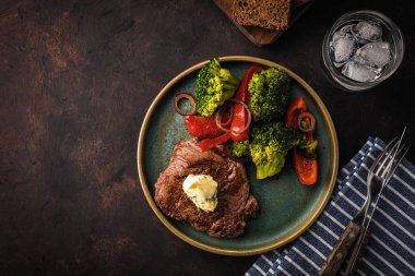 Sarımsak tereyağı ve sebze ızgara sığır eti biftek. Et ızgara dolmalık biber, brokoli ve soğan. Üstten görünüm. boşaltmak.