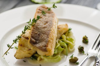 Beyaz tabak haşlanmış pırasa bir yastık üzerine pisi balığı fileto