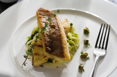 Beyaz tabak haşlanmış pırasa bir yastık üzerine pisi balığı fileto