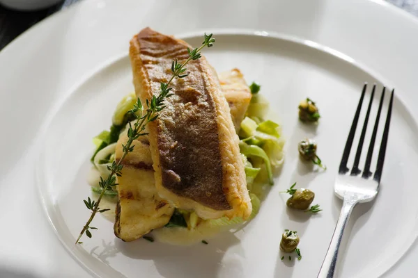 Beyaz tabak haşlanmış pırasa bir yastık üzerine pisi balığı fileto