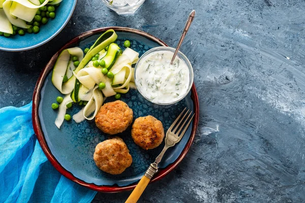 Chicken meat balls with zucchini salad and green peas, with garlic-yogurt sauce