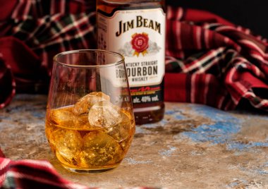 MINSK, BELARUS - OCTOBER 31, 2018: Bottle and glass Jim Beam is one of best selling brands of bourbon in the world, produced by Beam Inc. in Clermont, Kentucky clipart
