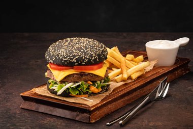 Domates ve salata ile siyah bir topuzun lezzetli taze sulu ev yapımı cheeseburger. Peynir ve Sebzeli Beef Burger