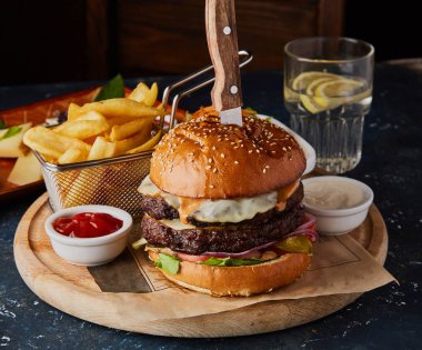 Yumurta ile çift sığır burger, kızarmış patates ve soslar masada