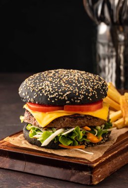 Domates ve salata ile siyah bir topuzun lezzetli taze sulu ev yapımı cheeseburger. Peynir ve Sebzeli Beef Burger